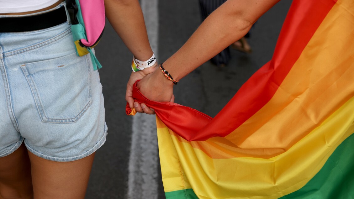 Due ragazze si tengono per mano in un Gay pride